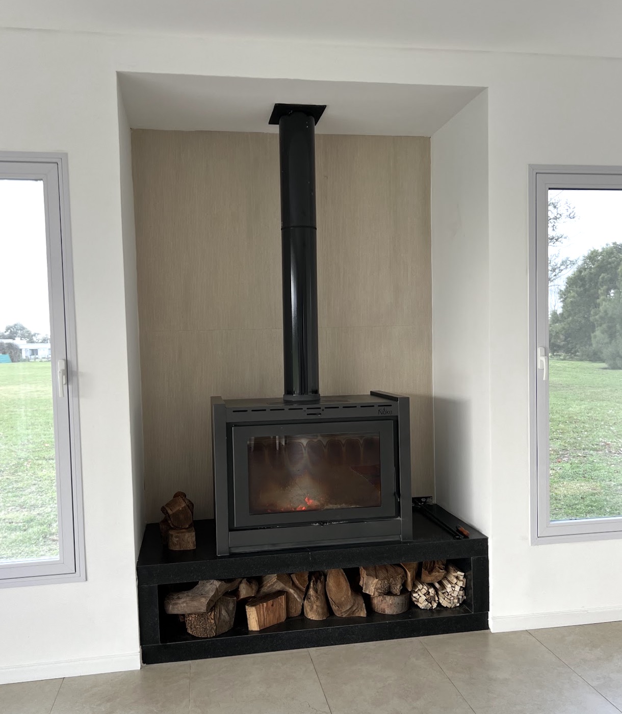 A real wood-burning stove with wood storage at the base, used as the reference for the design